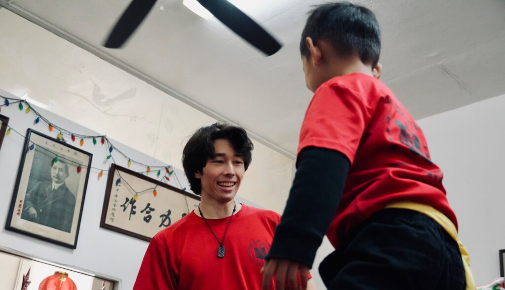 A more elder lion dancer playing with a much younger lion dancer at the historic CCBA building