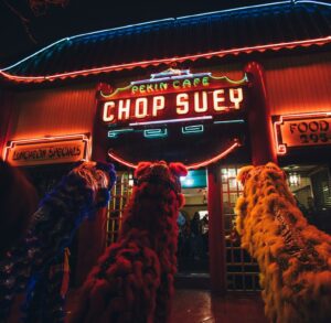 Lions approaching the historic Pekin Cafe with neon lights glowing at night.